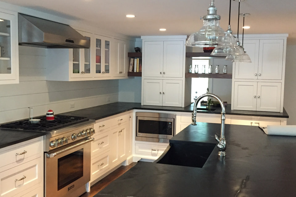 White custom kitchen cabinetry with black stone countertops