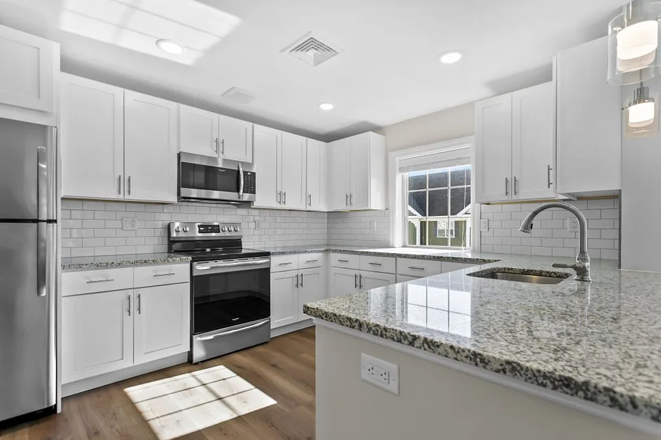 White kitchen cabinets with dark hardware and light-colored countertops.
