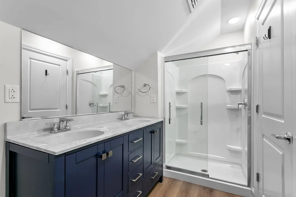 Dark double-vanity cabinetry beneath two mirrors, beside a white paneled door.