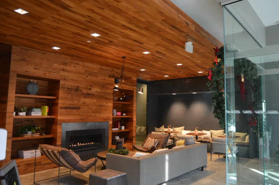 Lobby with wood-clad walls and ceiling, recessed shelves and a fireplace surround.