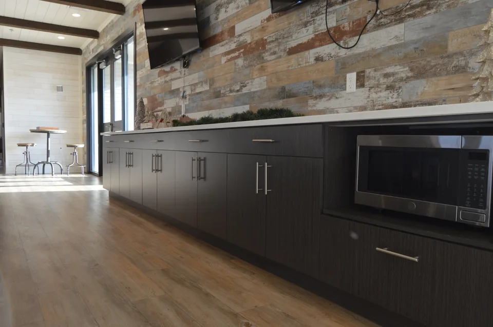 Long run of dark cabinets beneath a textured wall in a shared interior.