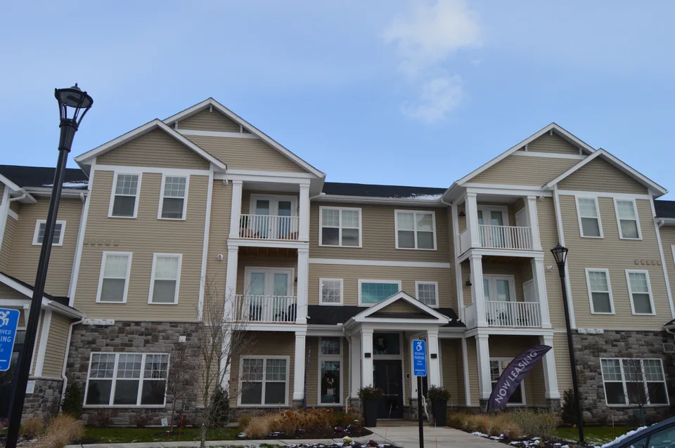 Multi-unit building with gabled rooflines, window surrounds and light-colored exterior trim.