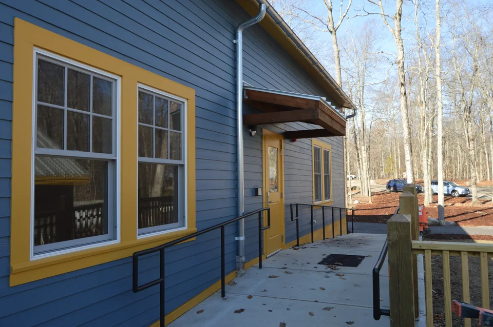 Blue-sided building with contrasting window trim and a covered entrance.