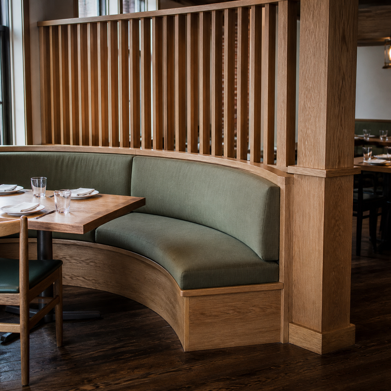 Commercial interior with a curved custom wood banquette and divider