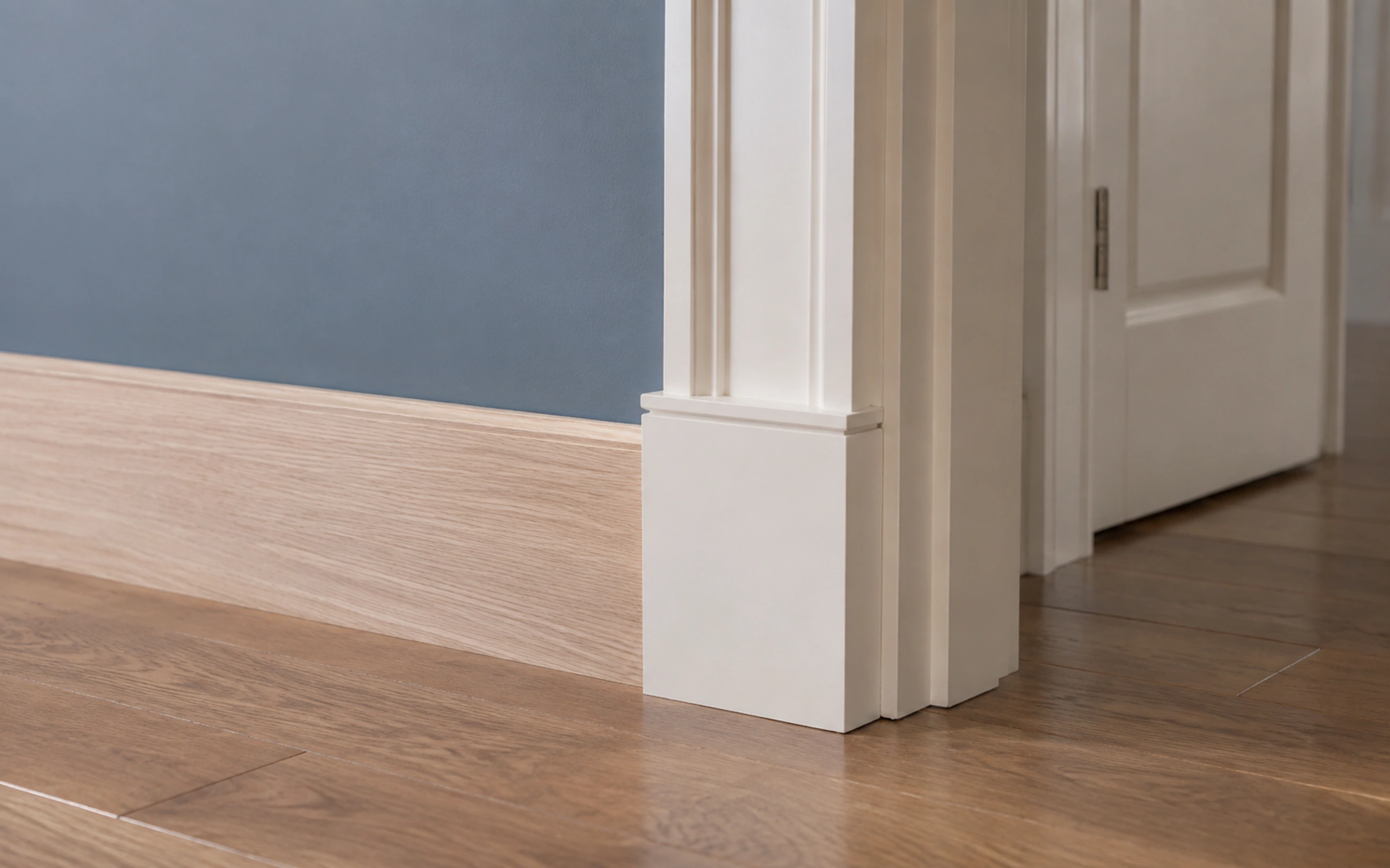 Wood baseboard meeting a door casing and plinth block.